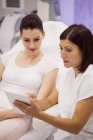 Female doctor using digital tablet to consulting patient in clinic — Stock Photo