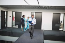 Doctor looking at medical report while walking in hospital corridor — Stock Photo