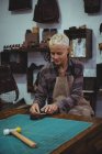 Handwerkerin bearbeitet in Werkstatt ein Stück Leder — Stockfoto