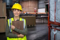 Portrait of young female worker holding clipboard in warehouse — Stock Photo
