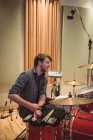 Lächelnder Schlagzeuger sitzt neben Schlagzeug bei Musikaufnahmen — Stockfoto