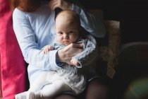 Seção média da mãe sentada com o bebê no quarto em casa — Fotografia de Stock