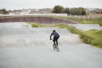 Visão traseira do ciclista andar de bicicleta BMX no parque de skate — Fotografia de Stock