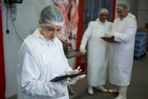 Técnico femenino usando tableta digital en fábrica de carne - foto de stock