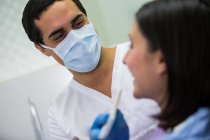 Крупним планом стоматолог вивчає пацієнта-жінку з моделлю відтінків зубів — стокове фото