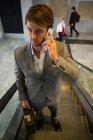 Uomo d'affari sulla scala mobile che parla sul cellulare in aeroporto — Foto stock