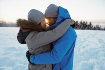 Casal romântico abraçando uns aos outros na paisagem nevada — Fotografia de Stock