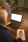 Donna che usa il computer portatile e scrive sul blocco note in ufficio — Foto stock