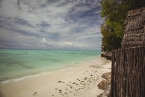 Рок и песчаный пляж у воды и голубого неба — стоковое фото