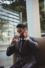 Бізнесмен має каву під час розмови на мобільному телефоні в офісних приміщеннях — стокове фото