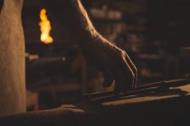 Hand of blacksmith holding tong in workshop — Stock Photo