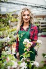 Retrato de florista feminina em pé no centro de jardim — Fotografia de Stock