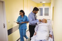 Medico che esamina il paziente anziano nel corridoio ospedaliero — Foto stock