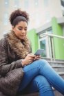 Low angle view of woman using phone while sitting on steps — Stock Photo
