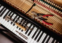 Close-up de ferramentas de reparação mantidos no teclado antigo piano — Fotografia de Stock