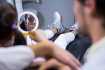 Paciente joven cepillándose los dientes con la asistencia del dentista en la clínica - foto de stock