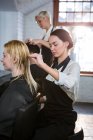 Перукарем розчісувати волосся клієнта в салон — стокове фото
