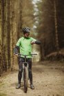 Frontansicht des Mountainbikers, der die Zeit während der Fahrt im Wald kontrolliert — Stockfoto