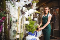 Портрет жіночого флориста, який влаштовує квіти в дерев'яній коробці в її квітковому магазині — стокове фото