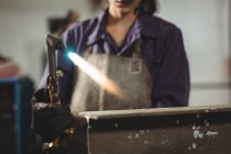 Sección media del soldador femenino que trabaja con metal en taller - foto de stock