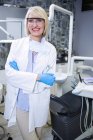 Portrait of smiling dentist standing with arms crossed at dental clinic — Stock Photo