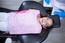 Висока кут зору посміхаючись молодих пацієнта лежачи на кріслі стоматолога в клініці — стокове фото