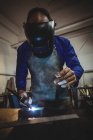 Soudeur masculin travaillant sur un morceau de métal en atelier — Photo de stock