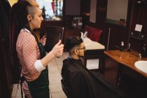 Парикмахер показывает мужчине свою стрижку в зеркале в парикмахерской — стоковое фото