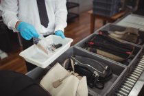 Sicherheitsbeamter hält Tablett mit Flüssigkeit und Schlüsseln im Flughafen — Stockfoto
