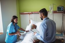 Медсестра утешает пожилого пациента с доктором в больнице — стоковое фото