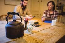 Teekanne auf einem Tisch zu Hause, im Hintergrund sitzt ein Paar — Stockfoto
