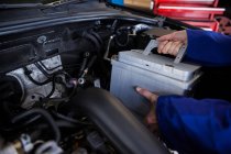 Immagine ritagliata di meccanico rimozione batteria auto da auto in officina di riparazione — Foto stock