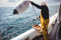 Fisherman throwing buoy into sea from fishing boat — Stock Photo