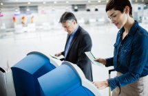 Personas de negocios que utilizan máquinas de facturación de autoservicio en el aeropuerto - foto de stock
