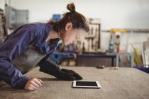 Female welder looking at digital tablet in workshop — Stock Photo