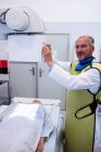 Врач-мужчина, использующий рентгеновский аппарат для обследования пациента в больнице — стоковое фото