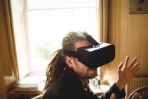 Primer plano del gesto hipster joven mientras se utiliza simulador de realidad virtual en casa - foto de stock