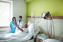 Doctor and nurse interacting over x-ray report with patient in hospital — Stock Photo