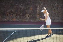 Женщина с теннисной ракеткой готова служить на спортивном корте — стоковое фото