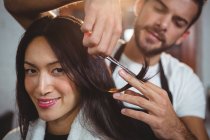 Женщине стригут волосы ножницами в салоне — стоковое фото