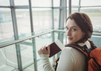 Portrait of woman with passport standing in waiting area at airport terminal — Stock Photo