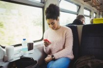 Bella donna che utilizza il telefono mentre seduto in treno — Foto stock