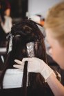 Female hairdresser dyeing hair of her client in salon — Stock Photo