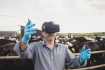 Operaio agricolo che indossa simulatore di realtà virtuale da recinzione contro il cielo — Foto stock