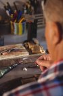 Goldsmith using hand piece machine in workshop — Stock Photo