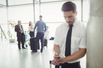 Pilota che utilizza il telefono cellulare nell'area di attesa del terminal dell'aeroporto — Foto stock