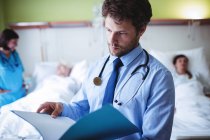 Doctor checking report in hospital ward — Stock Photo