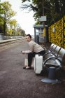 Mulher bonita sentado no banco na plataforma estação ferroviária — Fotografia de Stock