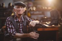 Portrait of shoemaker holding a shoemaker stand in workshop — Stock Photo