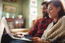 Couple shopping en ligne sur ordinateur portable dans le salon à la maison — Photo de stock